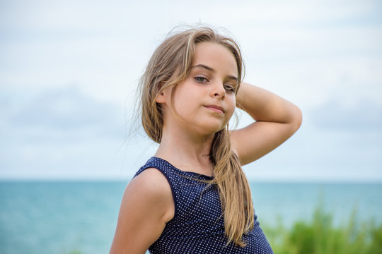 Crian&ccedil;a modelo sentada em frente ao mar azul