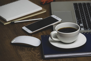 Top view table office with notebook, laptop, mobile, coffee cup, and pen with copy space on wooden table. Business concept.