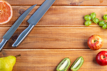 Rustic table of wooden strips with silver knives, with colorful fruits. Ripe and sweet fruits for desserts
