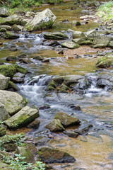 clear running waters of a creek in summer long exposure of water flowing over moss covered rocks