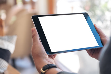 Mockup image of a woman's hands holding black tablet pc with blank white screen horizontally while sitting in cafe - obrazy, fototapety, plakaty