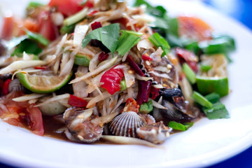 Papaya salad cockles in the plate have papaya salad cockles many have tomato cut large piece lemon parsley rough cut is a popular menu of thai people.