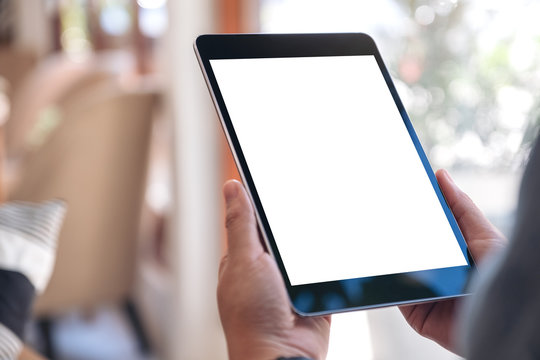 Mockup image of a woman's hands holding black tablet pc with blank white screen while sitting in cafe