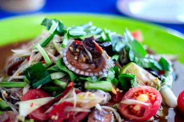 Papaya salad cockles in the plate have papaya salad cockles many have tomato cut large piece lemon parsley rough cut is a popular menu of thai people.