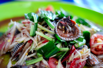 Papaya salad cockles in the plate have papaya salad cockles many have tomato cut large piece lemon parsley rough cut is a popular menu of thai people.