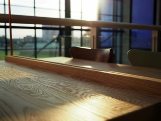Surface of bright wooden empty table in a posh, elegant cafe with flares of sunset, coffee shop 