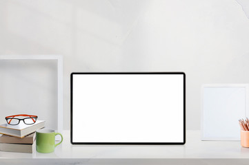 Mockup blank screen tablet on white wooden table  with supplies.