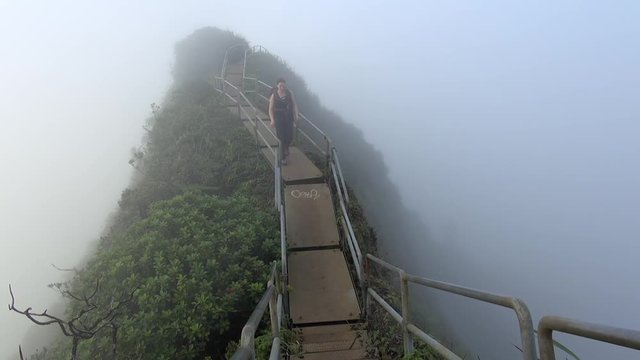 Young woman walks through cloud, high on the Haiku Stairs