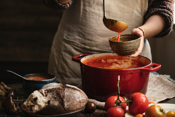Woman pouring tomato soup from a pot to a bowl