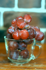 bunch of grapes in a transparent cup on a wooden table