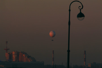 Fototapeta na wymiar balloon in the evening sky over the city at sunset