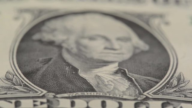 Extreme closeup of Washington on one dollar bill with focus moving from letters 'washington' up the picture of the president 