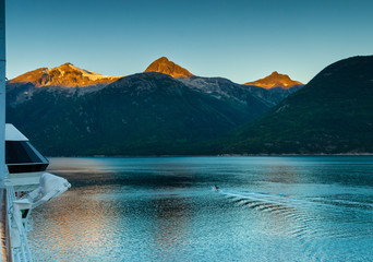 Fototapeta na wymiar Taiya Inlet, mountains and small craft on calm early morning from deck of cruise ship, Skagway, Alaska.