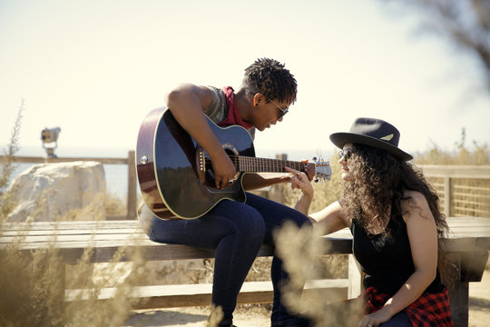 Two Women Playing Guitar and Flirting Outdoors