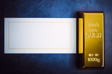 An ingot of gold metal bullion of pure brilliant on a gray textured background.