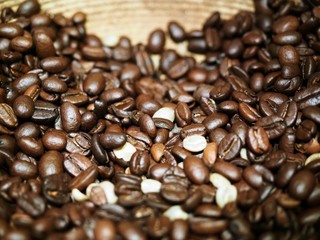 Roasted coffee beans in a wooden bowl, close up, coffee shop