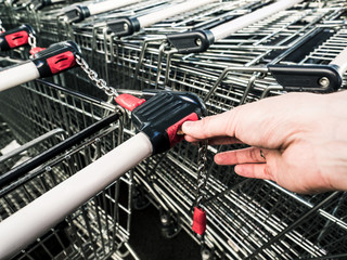 Inserting coin to Trolley, carts connected by chain in a big supermark