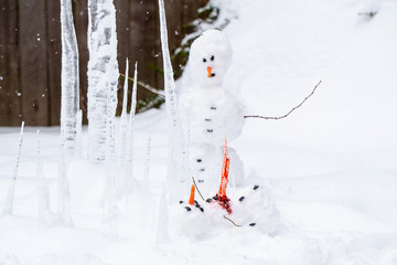Bloody dead snowman impaled on a sharp icicle during a winter storm