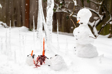 Bloody dead snowman impaled on a sharp icicle during a winter storm