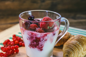 milk yogurt with raspberry jam and frozen strawberries and cherries. fresh vitamin breakfast.