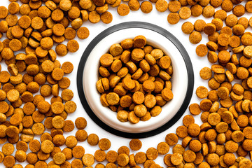 Dry dog food in bowl on white backgorund top view