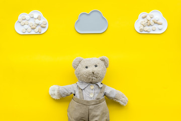Childhood diseases concept. Treatment of children.Teddy bear toy and pills on yellow background top view space for text
