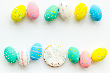 Easter symbols. Colorful Easter eggs and gingerbread on white background copy space border