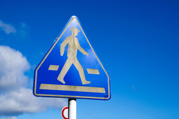 Signs of people crossing the road with blue sky background.