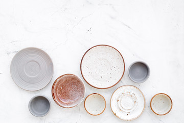 Kitchen concept. Crockery kit. Empty ceramic plates and mugs on white background top view copy space