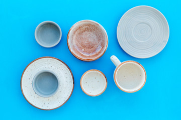 Kitchen concept. Crockery kit. Empty ceramic plates and mugs on blue background top view