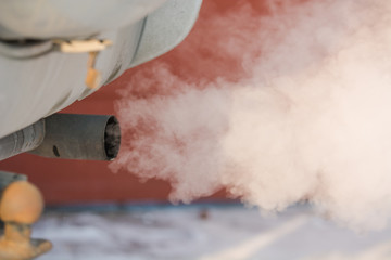 The car smokes in the winter. Smoke from a car pipe. The car is buzzing in the cold.