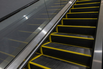 Escalator in the basement. Step up the escalator staircase. Yellow bars, steel bars, yellow iron bars