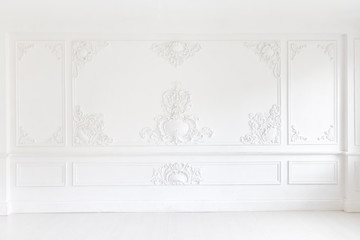 Beautiful ornate white decorative plaster mouldings in studio. The white wall is decorated with...
