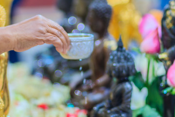 Close up hand of Thai people while bathing rite to buddha images in Songkran festival on the April 13 annual ritual every year. Buddhist is bathing a Buddha statue to gain merit during Thai New Year.
