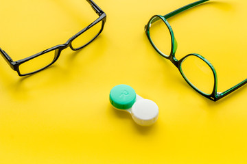 Eye problems. Glasses with transparent lenses and contact lenses on yellow background copy space