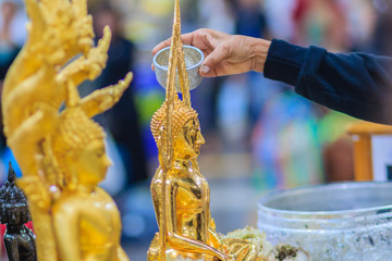 Close up hand of Thai people while bathing rite to buddha images in Songkran festival on the April 13 annual ritual every year. Buddhist is bathing a Buddha statue to gain merit during Thai New Year.