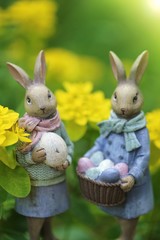 Easter holiday. Easter bunnies decorative on a blurred yellow   floral background in the bright rays of the sun. Spring season.