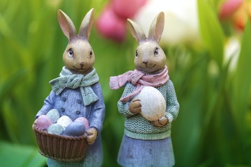 Easter holiday. Easter bunnies decorative on a blurred  floral background in the bright rays of the sun. Spring season.