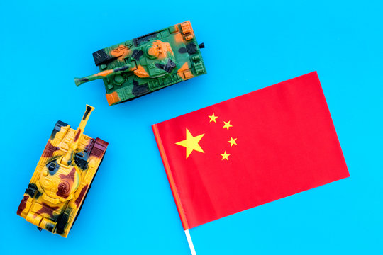 War, military threat, military power concept. China. Tanks toy near chinese flag on blue background top view