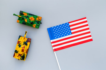 War, military threat, military power concept. USA. Tanks toy near american flag on grey background top view
