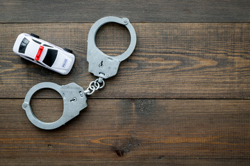 Police concept. Police car toy and handcuff on dark wooden background top view space for text
