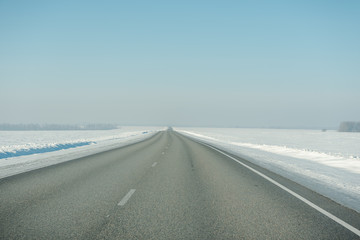 Fototapeta premium The road in winter. Asphalt road in winter. Road under the snow.