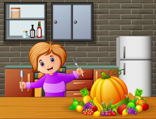 Happy little girl holding spoon and fork eating at the table