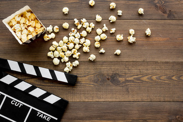 Film watching concept. Clapperboard and popcorn on dark wooden background top view copy space
