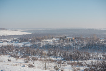 Obraz premium Winter view of the village from above. Houses in the snow. Countryside under the snow.