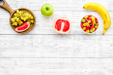 Fototapeta na wymiar Food rich by vitamins and fiber. Healthy food. Fruit salad near fresh fruits on white wooden background top view copy space