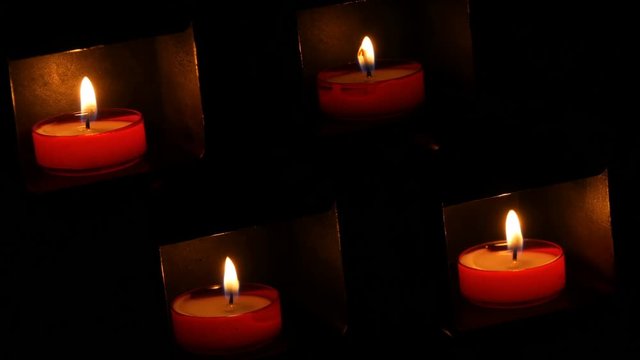 Burning beautiful red round prayer candles in a special niche in the darkness of a Catholic church