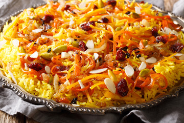 Persian vegetarian festive jeweled rice with dried fruits, carrots, orange zest and nuts closeup on a plate on the table. horizontal