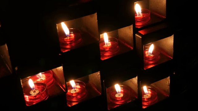 Burning beautiful red round prayer candles in a special niche in the darkness of a Catholic church