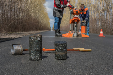 Worker cut by the core sampler samples of asphalt concrete on the road. Asphalt concrete cores...